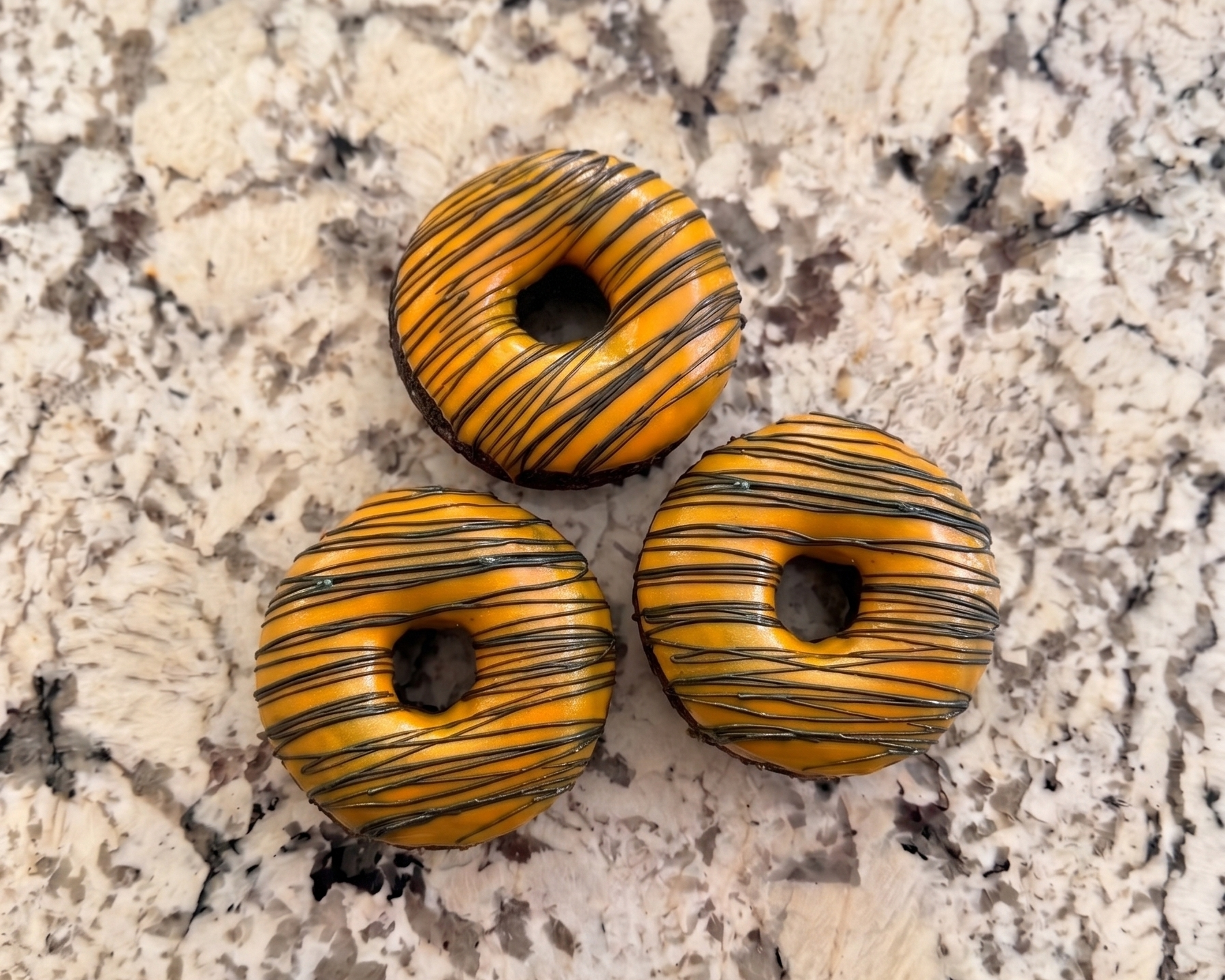 Three striped donuts on a marble surface