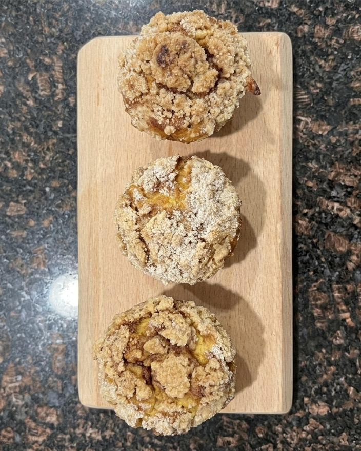 Three muffins on a wooden board with a granite countertop background